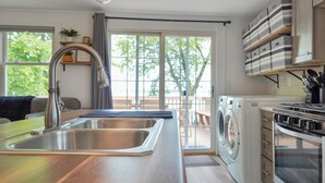 A modern kitchen with a stainless steel sink, a built-in oven, and a washing machine. - The Lake House at Darling Shores (Alexandria)