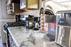 A kitchen with a marble countertop, a coffee machine, a kettle, and a toaster.