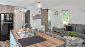 A modern kitchen with a black refrigerator, wooden countertop, and a dining area with a table and chairs. - The Lake House at Darling Shores (Alexandria)