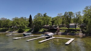 A lakeside property with docked boats, a covered boat house, and residential buildings in the background. - The Lake House at Darling Shores (Alexandria)