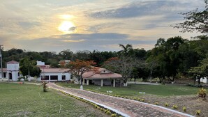 A residential area with a paved pathway, a house with a red-tiled roof, and surrounding greenery. - HOTEL CAMPESTRE LAS PALOMAS (Tocaima)
