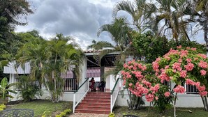 A building with a staircase leading to a covered area, surrounded by lush greenery and pink flowering plants. - HOTEL CAMPESTRE LAS PALOMAS (Tocaima)