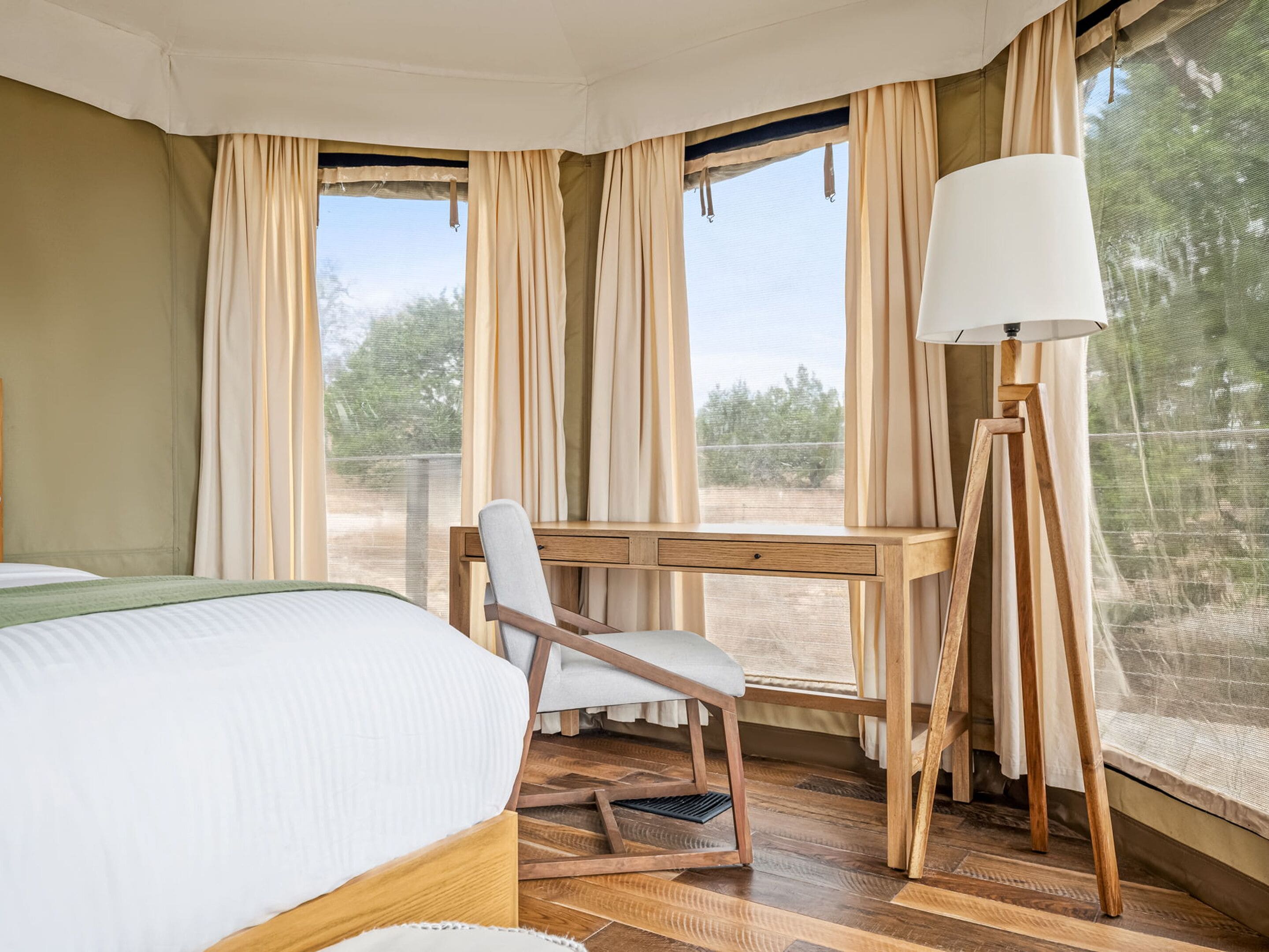 A bedroom with a bed, a desk, a chair, and a lamp.