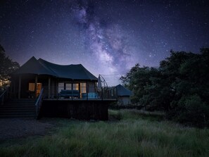 A two-story building with a covered porch and a large window, set against a starry night sky.