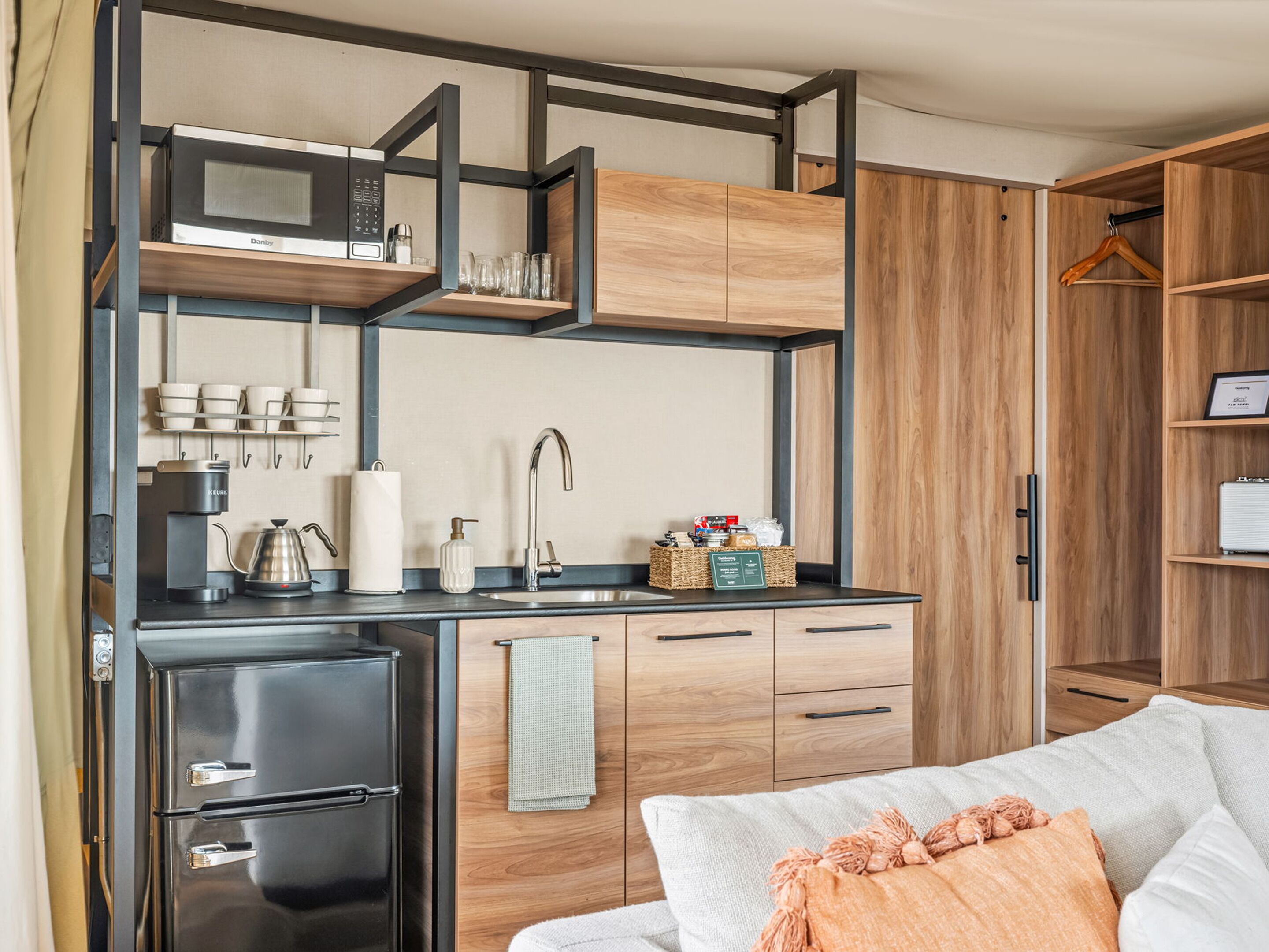 A compact kitchenette with a microwave, coffee maker, and storage cabinets.