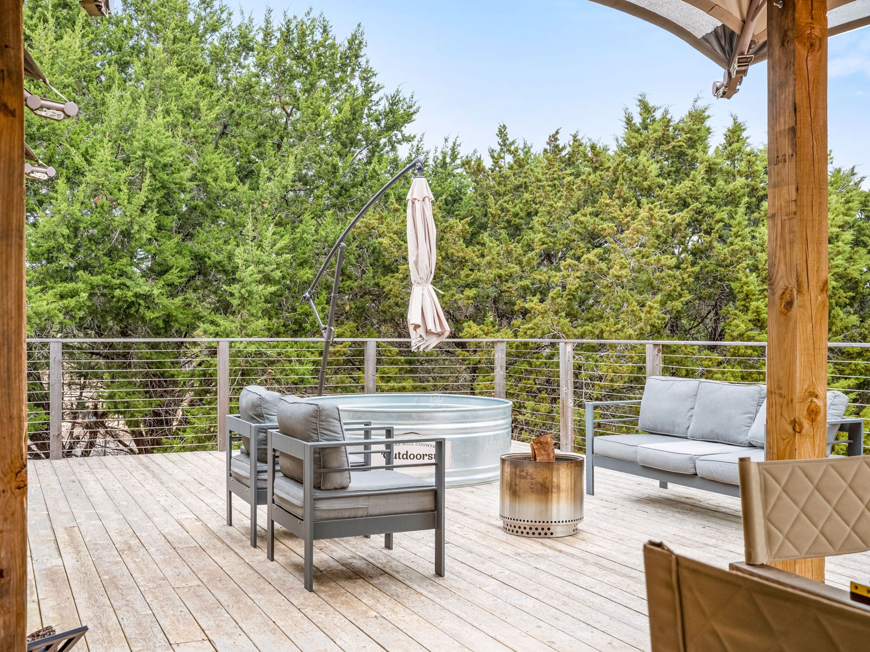 A wooden deck with a hot tub, outdoor seating, and a pergola.