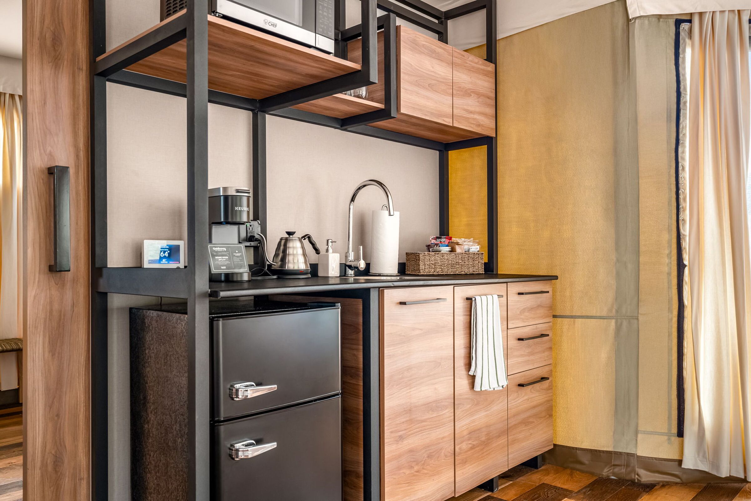 A modern kitchen with a black countertop, wooden cabinets, and a built-in coffee maker.