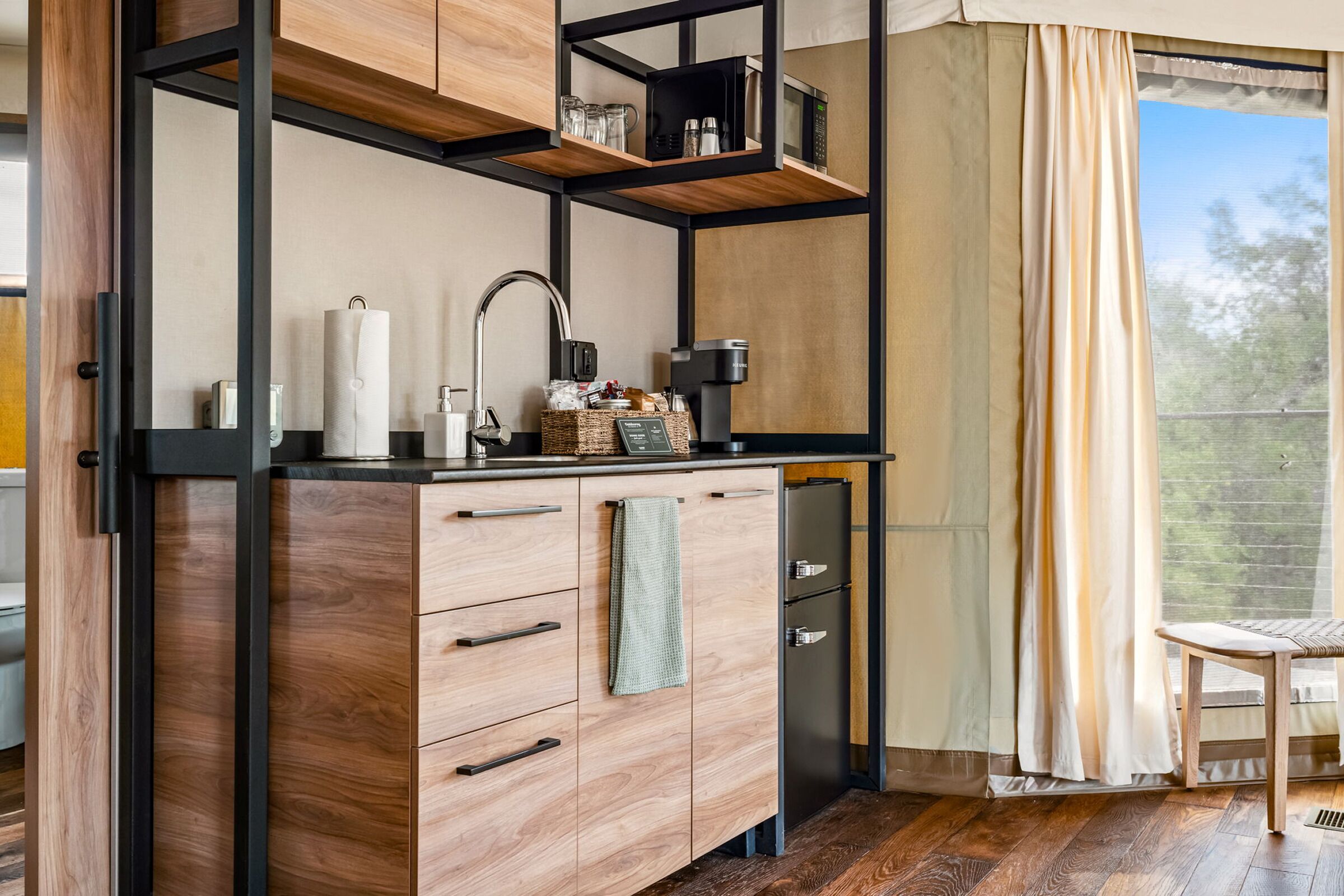 Una cocina moderna con armarios de madera, microondas integrado y cafetera.