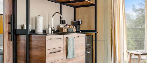 Una cocina moderna con armarios de madera, microondas integrado y cafetera.