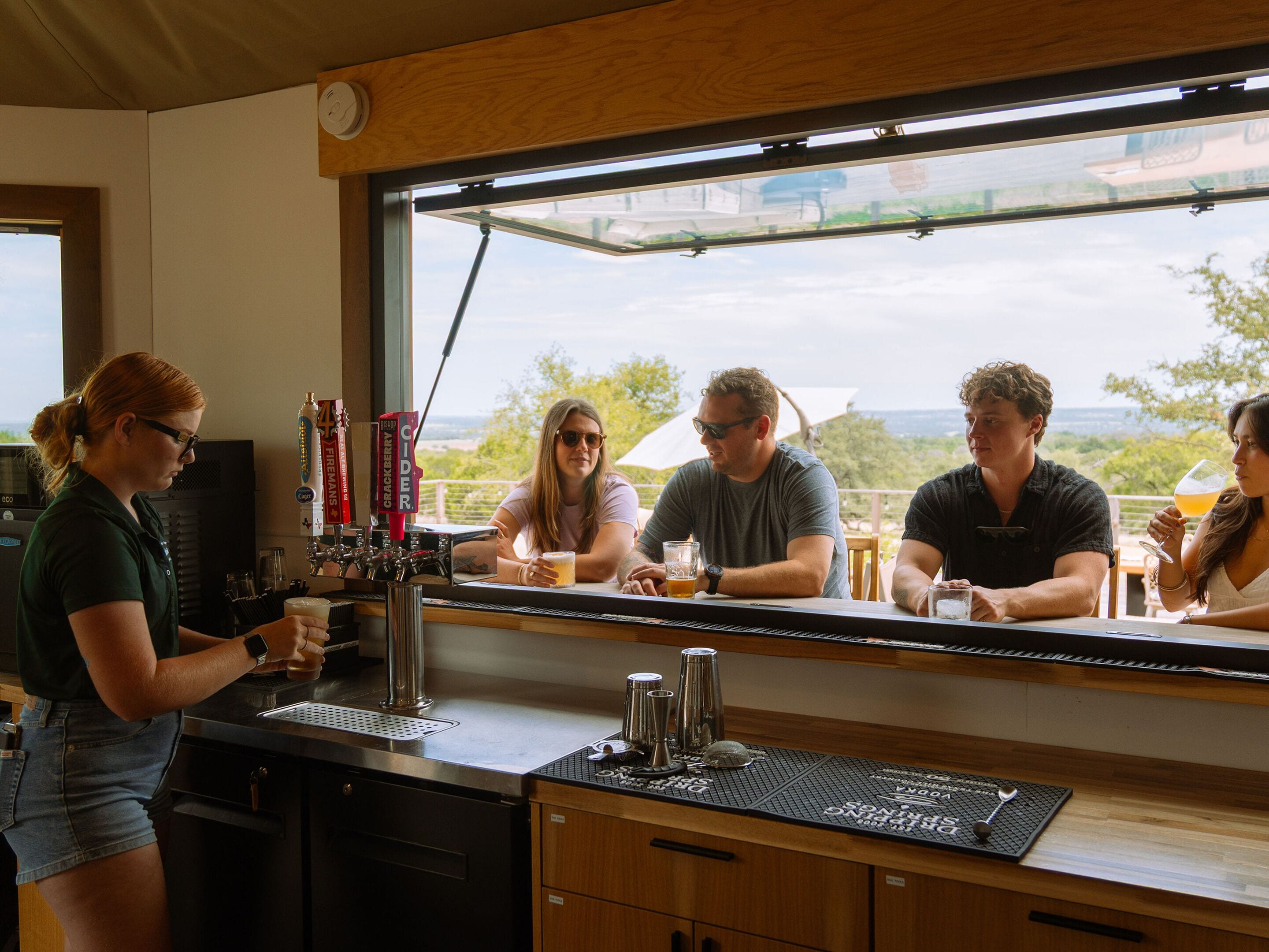 Un espace bar avec un comptoir, une tireuse à bière et une vue sur l’extérieur.
