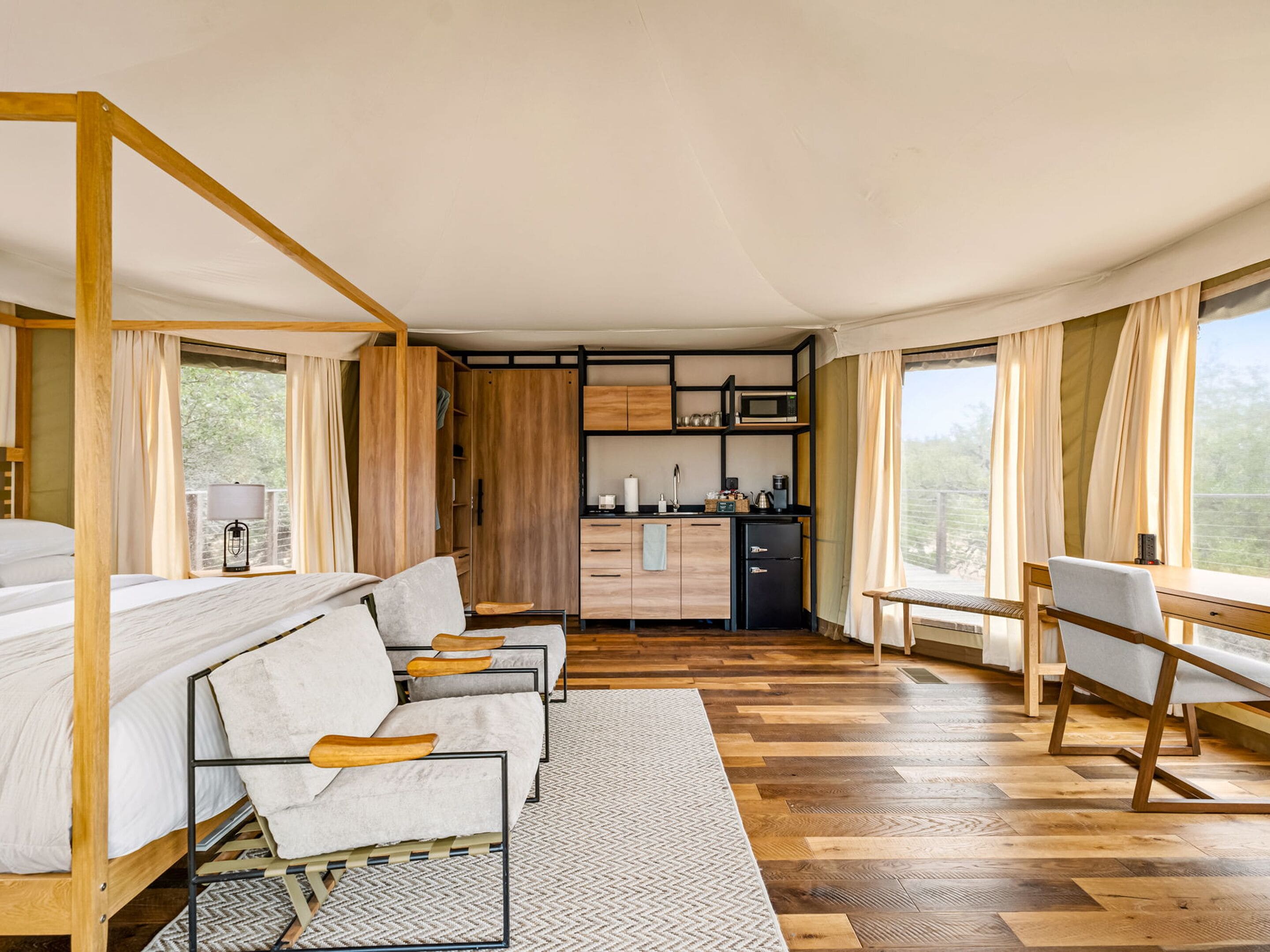 A bedroom with a large bed, a desk, and a kitchenette.