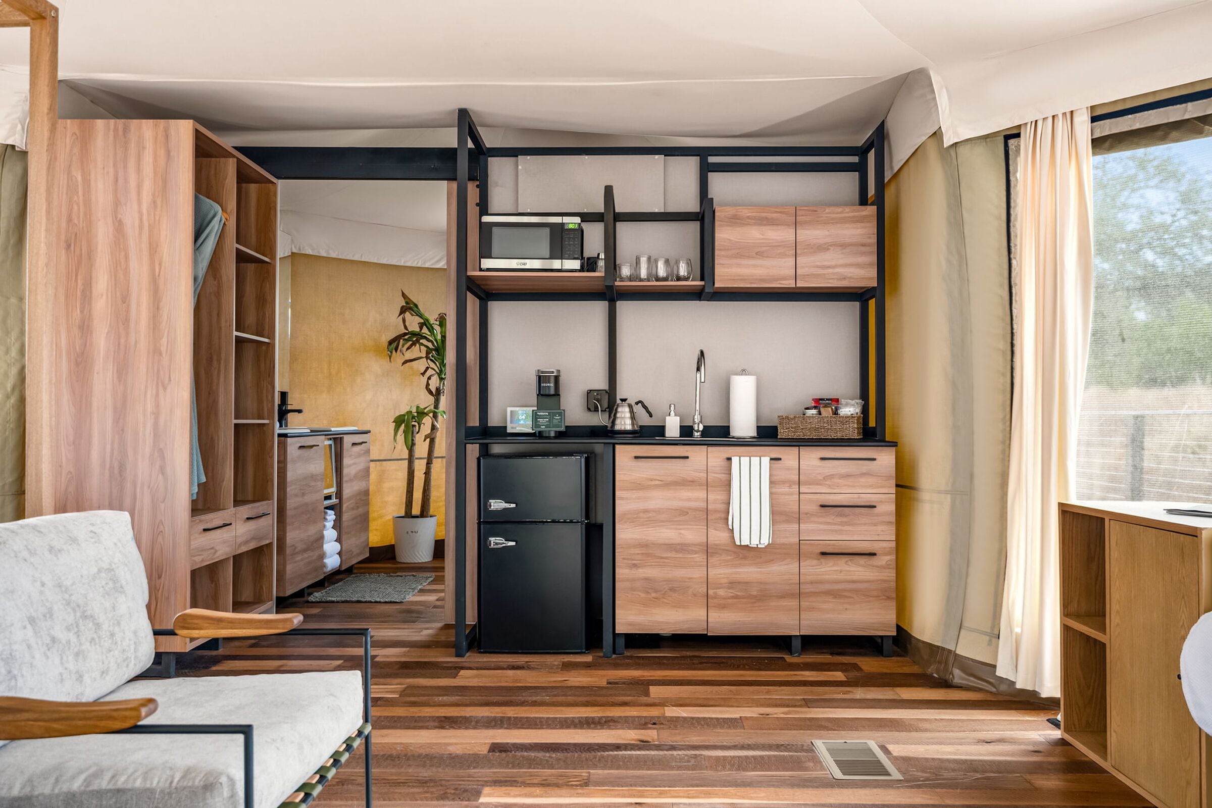 A compact kitchen with a microwave, refrigerator, and wooden cabinets.