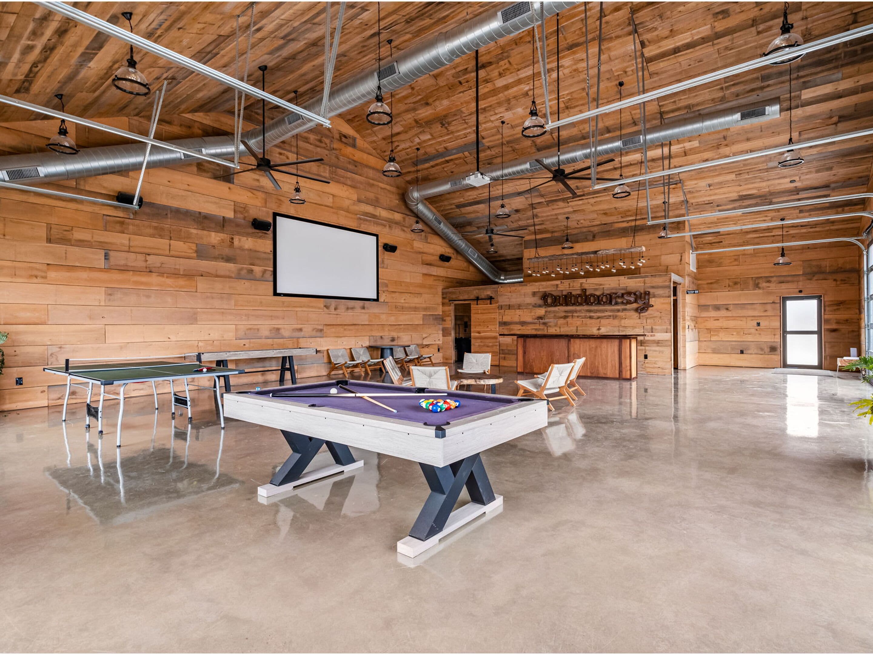 A spacious indoor area with a pool table, ping pong table, and seating area.