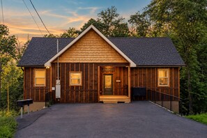 Une cabane en bois avec un porche à l’avant, un toit sombre et une boîte aux lettres.