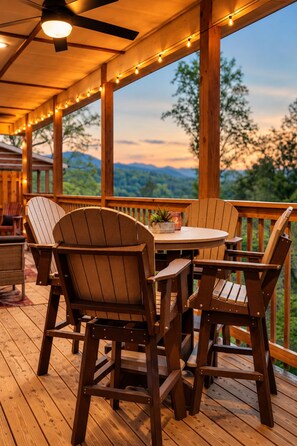 A wooden deck with Adirondack chairs and a table, overlooking a mountainous landscape. - Free Dollywood Tix/Luxe/Spacious/Modern/Game Room (Gatlinburg)
