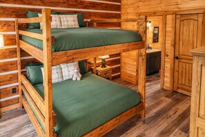 Un lit superposé avec une literie verte et un jouet en peluche sur le lit du bas.