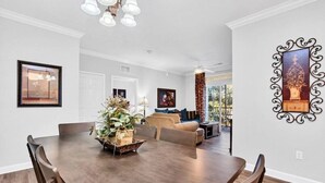 Un coin repas avec une table et des chaises en bois, un lustre et une plante décorative en guise de centre de table.