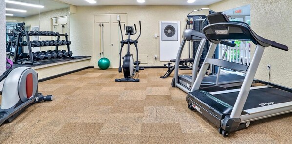 Un gimnasio con cintas de correr, mancuernas y una bicicleta estática.