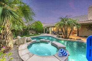 Relax by the pool surrounded by lush greenery and palm trees, with a hot tub and swimming pool at your fingertips.