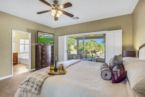 Relax in this inviting space with a large bed, ceiling fan, and wall-mounted TV, plus a patio view.