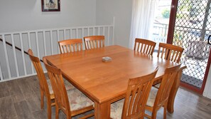 Enjoy meals in this dining area with a table and six chairs, a framed picture on the wall, and a glass door leading to the outdoors.