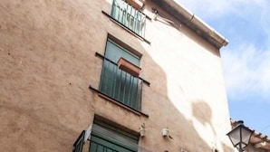A building with a stone facade, a small balcony with green shutters, and a door with a number plate. - Tradicional house in Prat de Comte (Prat de Comte)