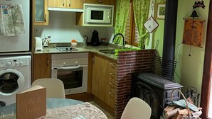 A compact kitchen with a microwave, oven, and washing machine. There is a dining table with chairs and a menu on it. - Tradicional house in Prat de Comte (Prat de Comte)
