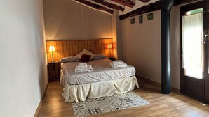 A well-lit bedroom with a wooden ceiling, a bed with neatly folded towels, and a patterned rug. - Tradicional house in Prat de Comte (Prat de Comte)