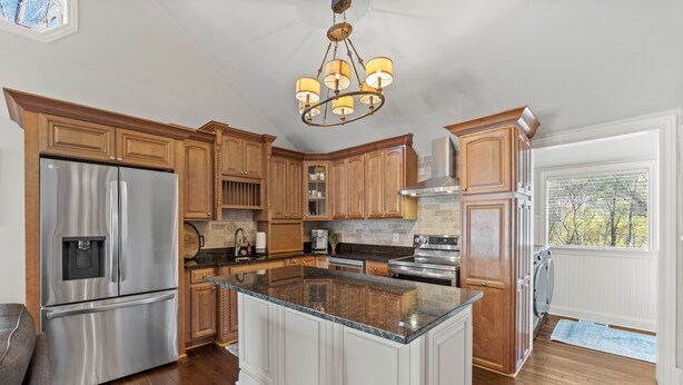 A spacious kitchen with wooden cabinets, stainless steel appliances, and a large island. - Cook Cottage (Stockbridge)