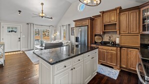 A spacious kitchen with wooden cabinets, a large island, and a built-in refrigerator. - Cook Cottage (Stockbridge)