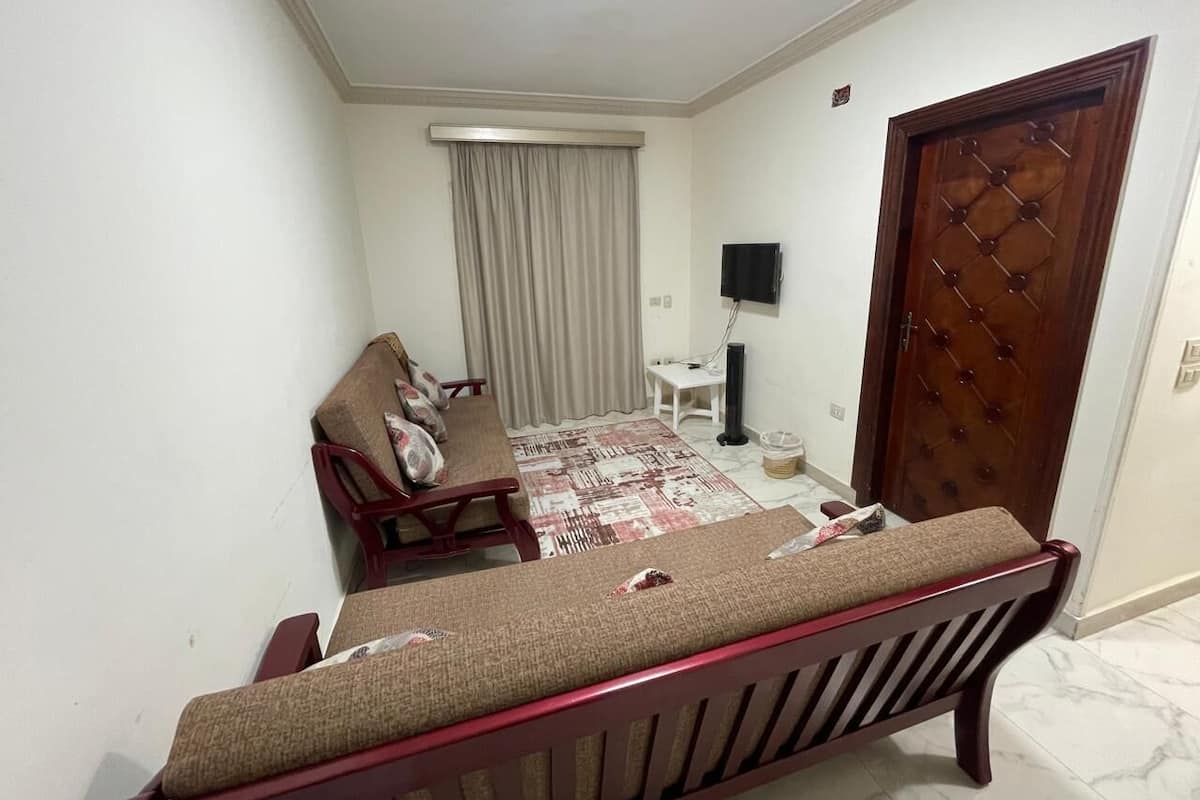 A small, compact room with a bed, a chair, a small table, and a television.