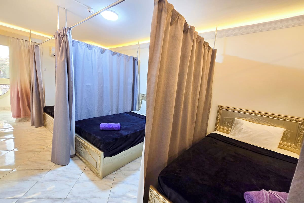A hotel room with two beds, a balcony, and a view of the city.