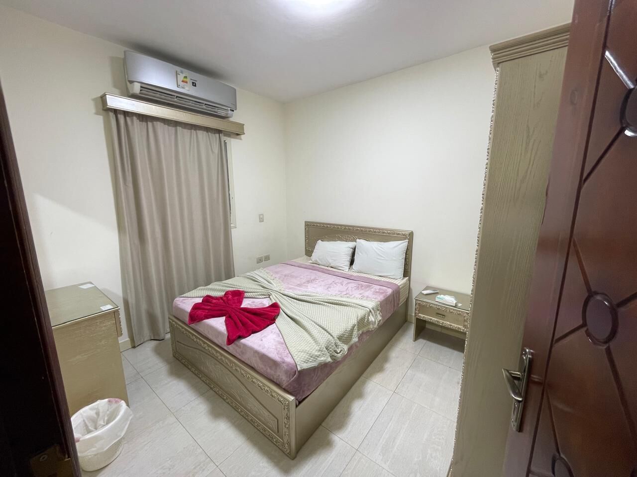 A neatly arranged bedroom with a bed, bedside table, and an air conditioning unit.
