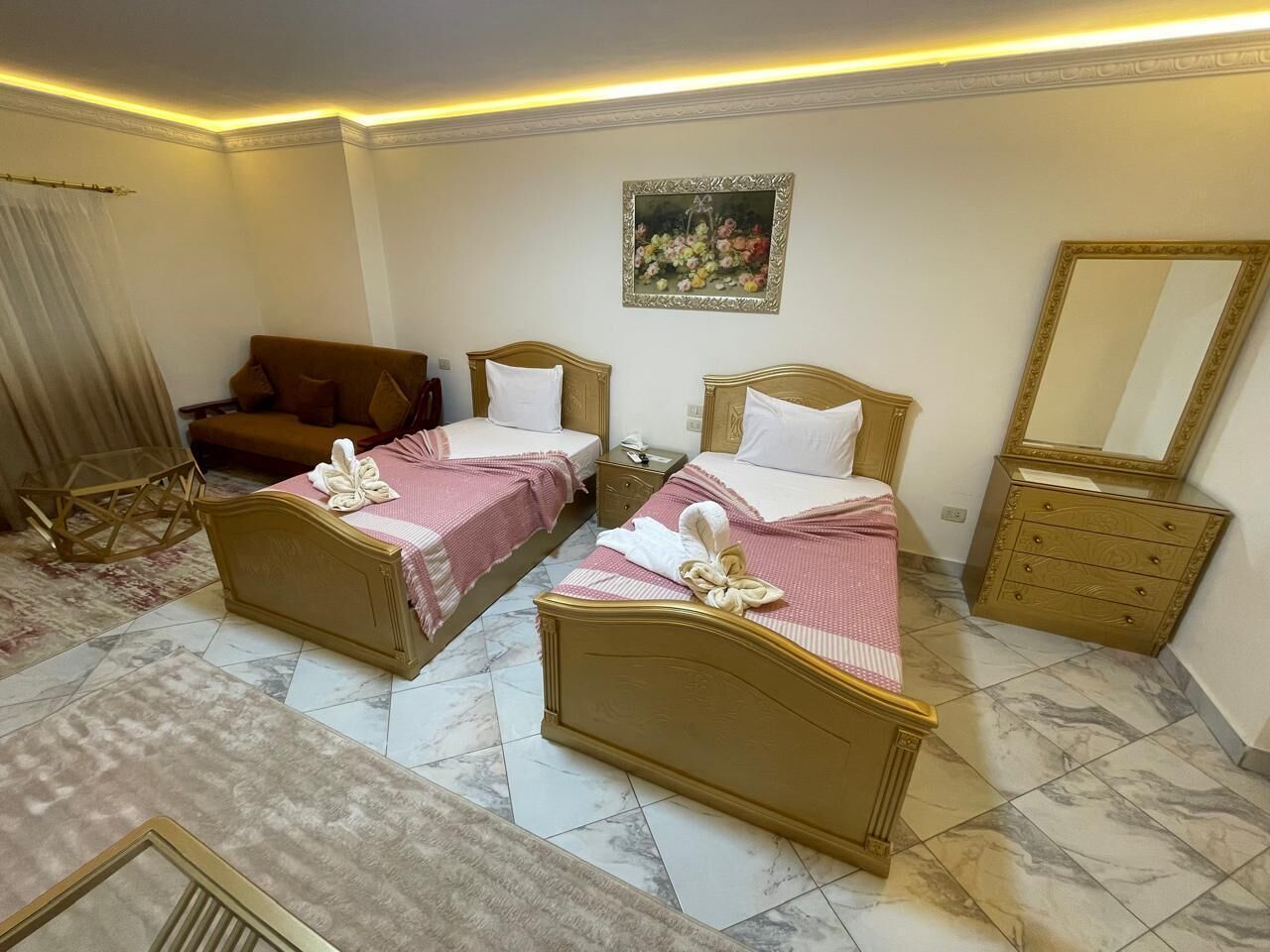Ein Hotelzimmer mit zwei Betten, einem Schlafsofa, einem Spiegel und einem Bild an der Wand.