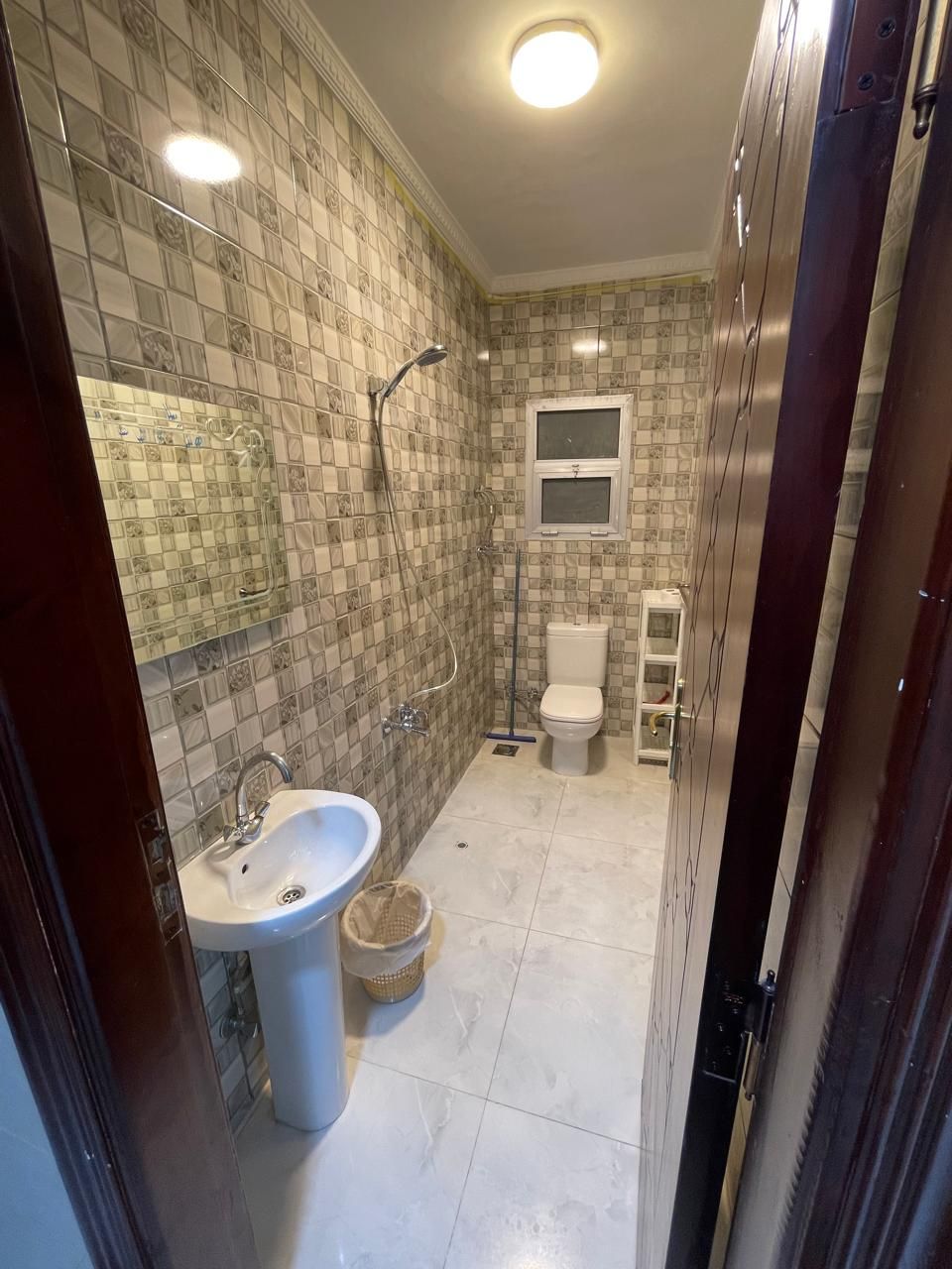 Une salle de bain avec un mur carrelé, un lavabo, des toilettes et une douche.