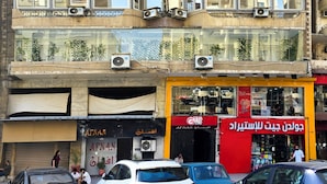 A multi-story building with balconies, air conditioning units, and a storefront with a red sign. - Afnan Cairo Airport (Cairo)
