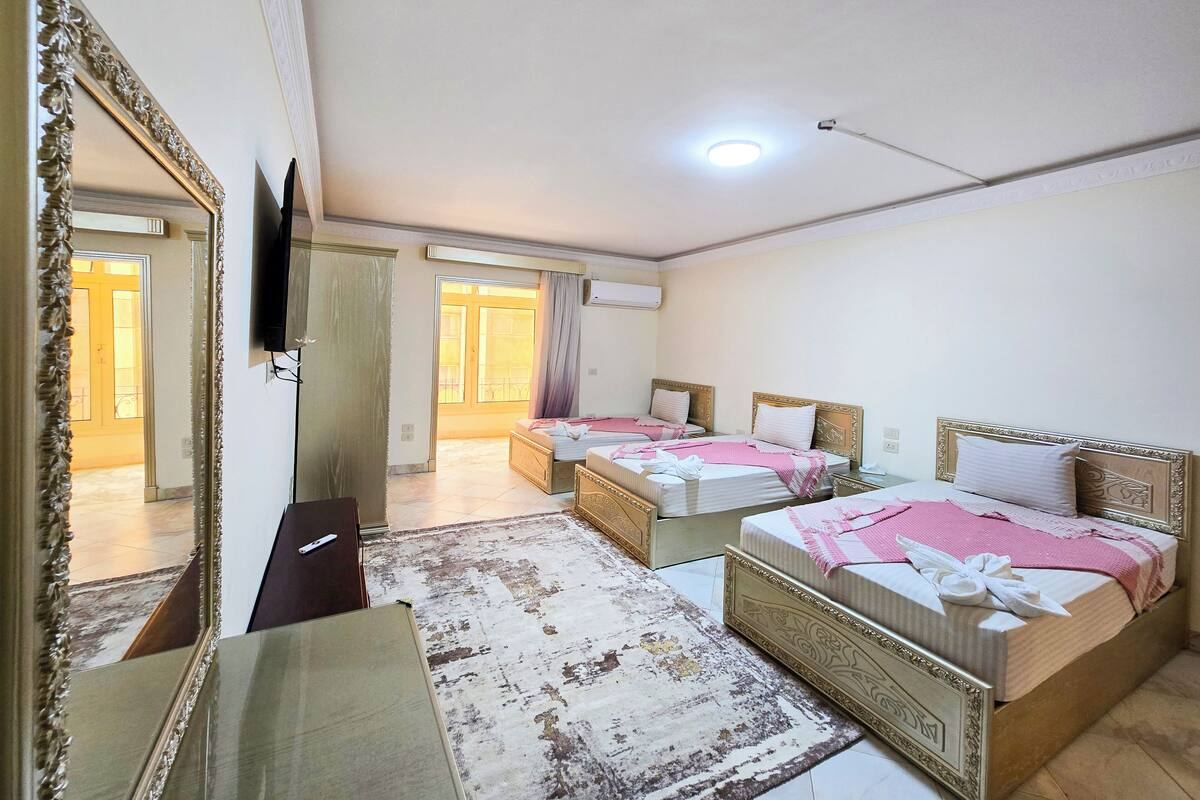 A hotel room with two beds, a large mirror, a flat-screen TV, and a view of the outside.
