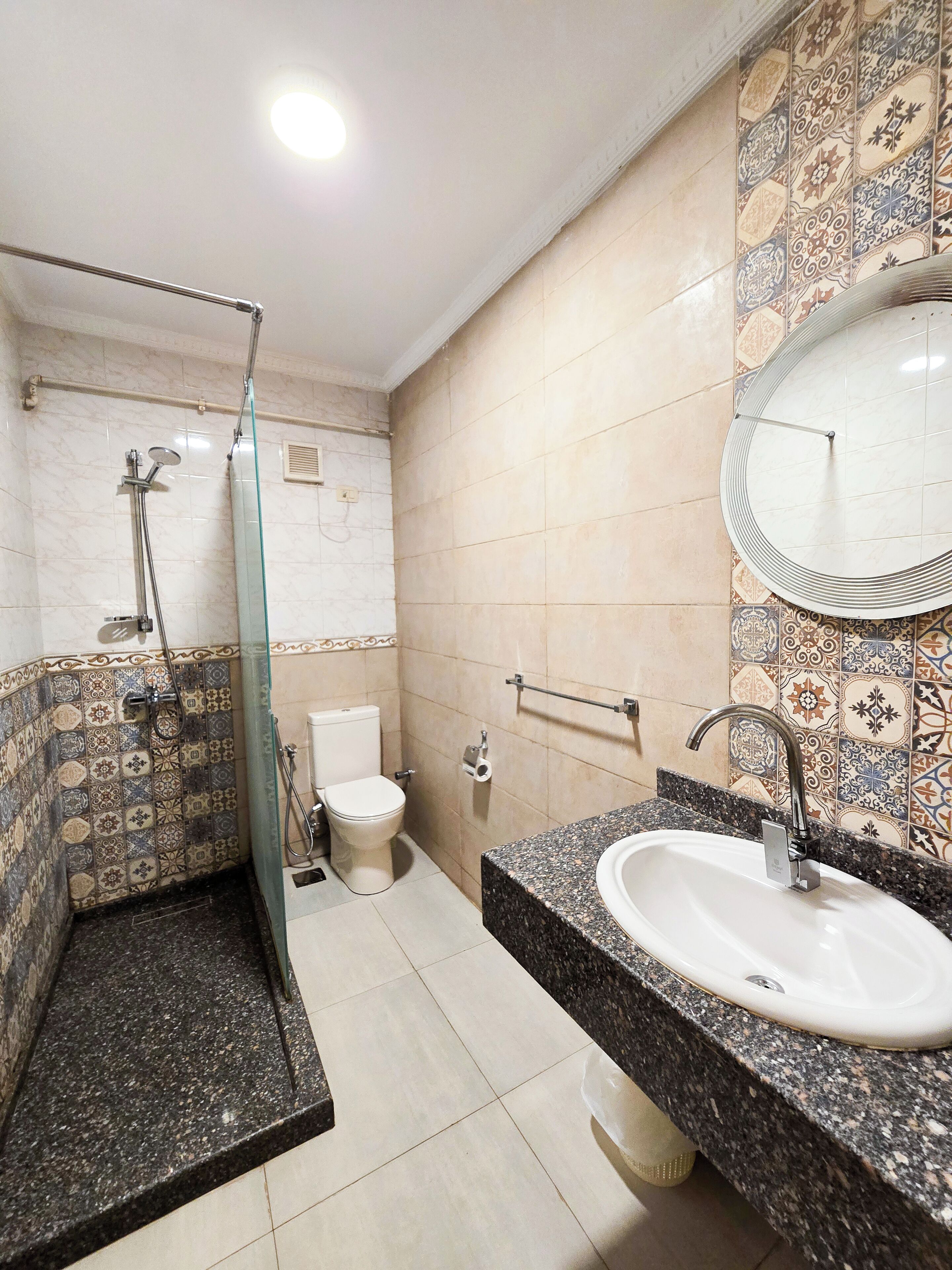 A bathroom with a shower, toilet, sink, and a mirror.