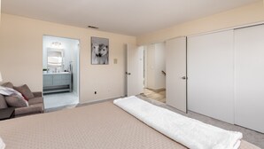 Une chambre avec un grand lit, une salle de bain avec un miroir et un lavabo, et un placard.