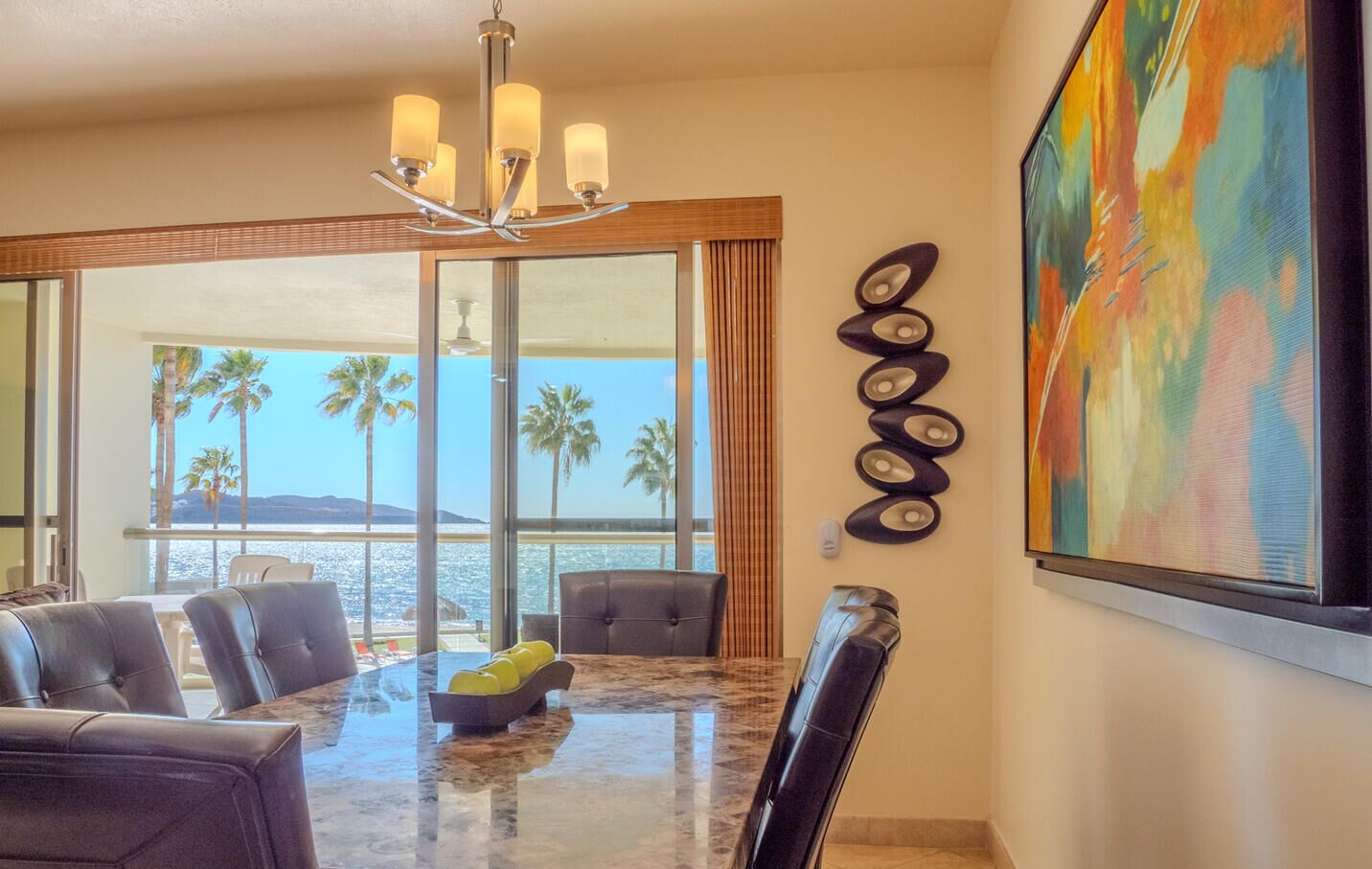 Uma sala de jantar com uma mesa grande, cadeiras e vista para o oceano.
