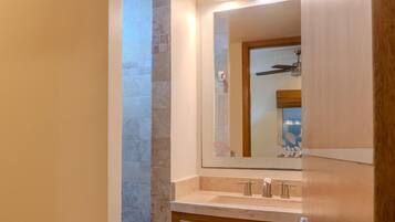 Un baño con tocador de madera, un espejo y pared con azulejos.
