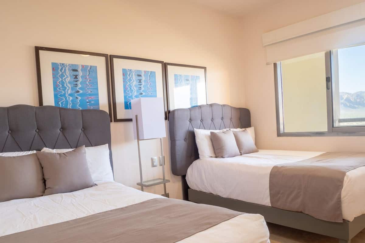 Ein Hotelzimmer mit zwei Betten, einem großen Fenster und Bildern an der Wand.