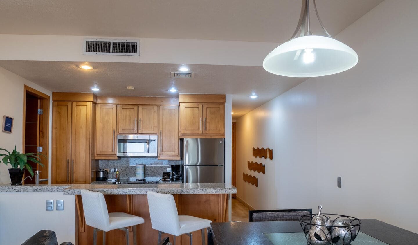 Una cocina moderna con armarios de madera, electrodomésticos de acero inoxidable y una zona de comedor con una mesa y sillas.