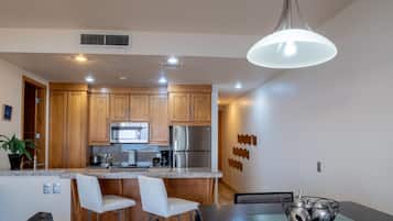 Una cocina moderna con armarios de madera, electrodomésticos de acero inoxidable y una zona de comedor con una mesa y sillas.