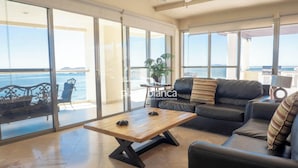 Un salon spacieux doté d’une grande porte-fenêtre coulissante donnant sur un balcon avec vue sur la mer.