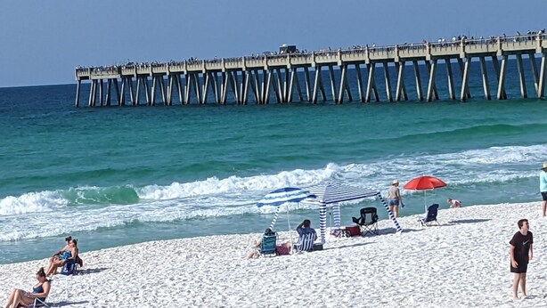 Una playa con un muelle al fondo.