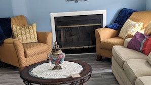 Una sala de estar con chimenea, dos sofás, una mesa de centro y un espejo decorativo.
