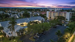 Un hotel con estacionamiento, varias edificaciones y vistas al atardecer.