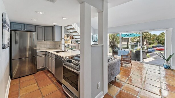 Una cocina moderna con electrodomésticos de acero inoxidable, una isla grande y vistas a un patio exterior.