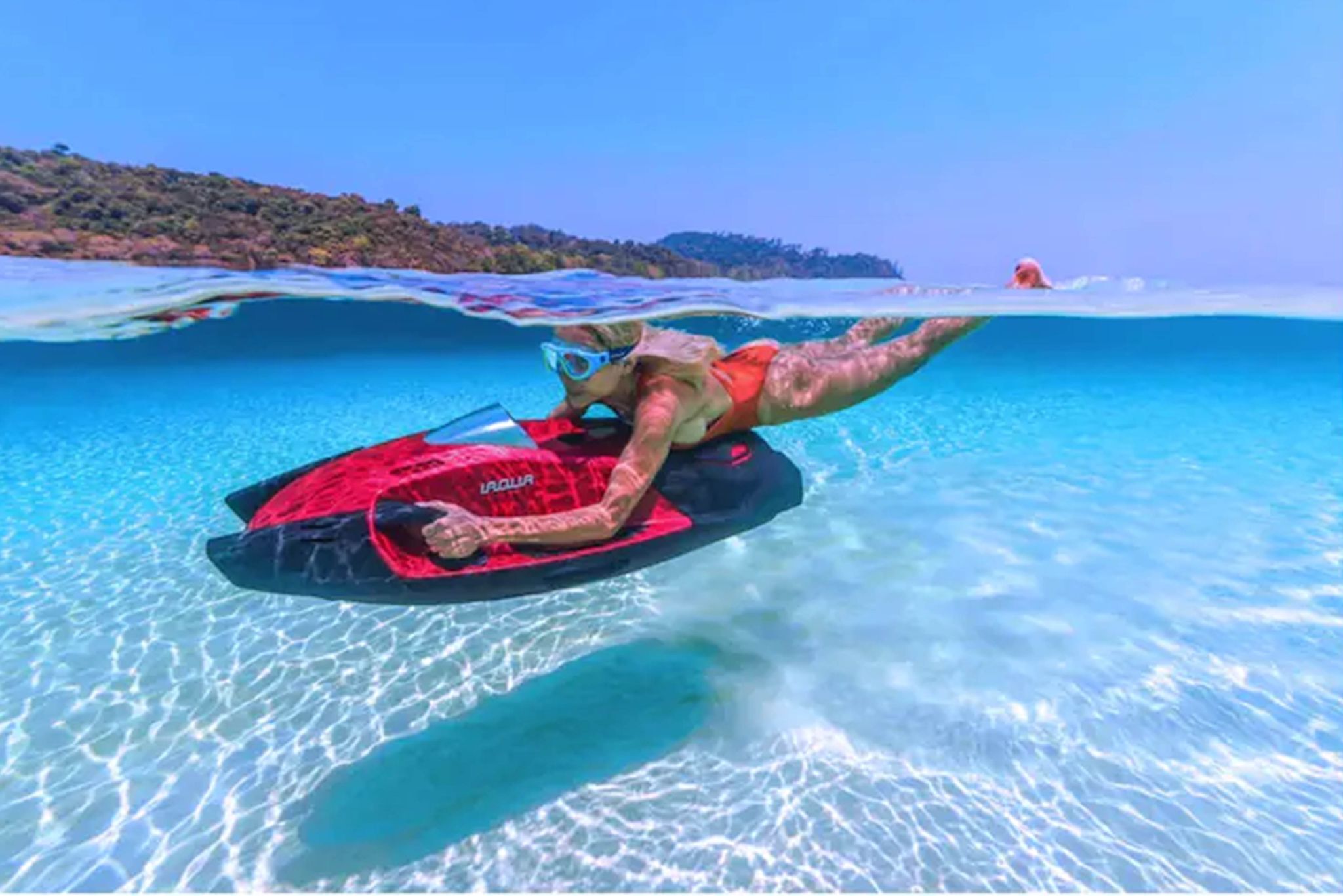 A person riding a red jet ski on clear blue water.